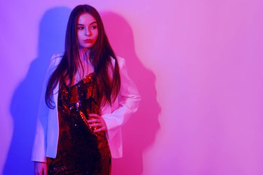 Kırmızı elbiseli, pullu, beyaz ceketli, gece kulübünde dans eden güzel bir esmer. Neon ışıklı kız. Metin için alanı kopyala.