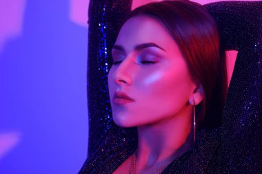 Büyük dudakları, mükemmel kaşları, büyük küpeleri ve pirzolaları olan muhteşem bir esmerin portresi. Her gece dans eden, neon ışıkta şarkılarla dans eden şık bir kız. Bir parti..
