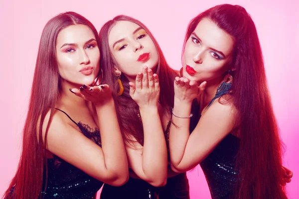 3 girls pose, send kisses. Girls in brilliant dresses with different colorful makeup. Three brunette girls dance and enjoy life. March 8, women\'s power, Women\'s Day.