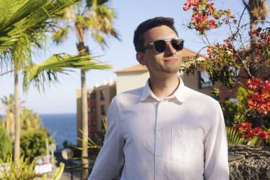 Beyaz gömlekli ve arka planda siyah gözlüklü bir adam sıcak bir gün geçirir. Adam seni bekliyor. Tropiklerde bir adam hayatın tadını çıkarır, yalnız tatilin. Adam tek başına dinleniyor..