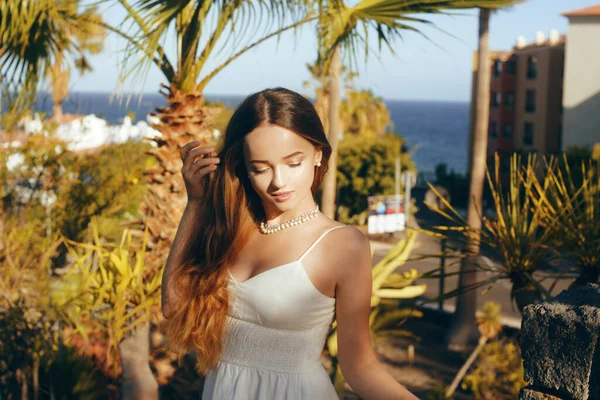 美丽的长发姑娘 背景是温暖国度的棕榈树 热带女孩 阳光和夏天 风在她的头发 女孩独自旅行 Honeymoon 穿白衣的女孩 — 图库照片