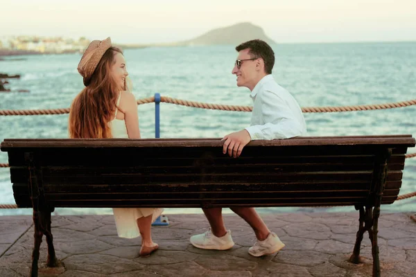 一对夫妇坐在海洋交流的背景上 度蜜月的概念 一个女孩和一个男人坐在长椅上 在大海和高山的背景下大笑 西班牙 金丝雀 白衣情侣 — 图库照片