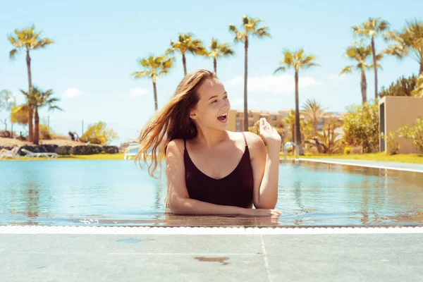 游泳池里快乐的女孩 金发碧眼穿着红色游泳衣 这个女孩喜欢旅行 有棕榈树背景的女孩 — 图库照片