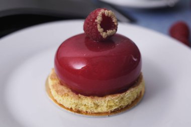 Bisküvinin üzerinde nefis bir kırmızı diyet tatlı. Tatlı olarak ahududu, mavi arka planda ahududu. Latte, yarın, tatlı için cihazlar. Yemek fotoğrafı. Kahvaltı, tatlım..