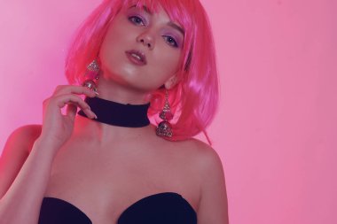 Siyah şık bir elbise içinde pembe kısa saçlı bir manken. Havalı kız poz veriyor. Çok parlak bir görüntü. Pembe geçmişi olan şarlatan bir kız. Baştan çıkarıcı kız. Yakalı şık siyah elbise..