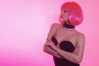 Siyah şık bir elbise içinde pembe kısa saçlı bir manken. Havalı kız poz veriyor. Çok parlak bir görüntü. Pembe geçmişi olan şarlatan bir kız. Baştan çıkarıcı kız. Yakalı şık siyah elbise..