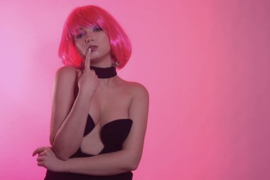 Siyah şık bir elbise içinde pembe kısa saçlı bir manken. Havalı kız poz veriyor. Çok parlak bir görüntü. Pembe geçmişi olan şarlatan bir kız. Baştan çıkarıcı kız. Yakalı şık siyah elbise..