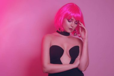 Siyah şık bir elbise içinde pembe kısa saçlı bir manken. Havalı kız poz veriyor. Çok parlak bir görüntü. Pembe geçmişi olan şarlatan bir kız. Baştan çıkarıcı kız. Yakalı şık siyah elbise..