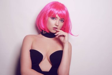 Beyaz arka planda bir kız, profesyonel model. Pembe saçlı kız, gizemli, güzel, kameraya bakıyor, flört ediyor, flört ediyor. Uzun pembe küpeler. İnanılmaz bir bakış..