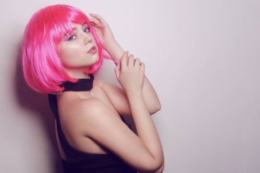 Beyaz arka planda bir kız, profesyonel model. Pembe saçlı kız, gizemli, güzel, kameraya bakıyor, flört ediyor, flört ediyor. Uzun pembe küpeler. İnanılmaz bir bakış..