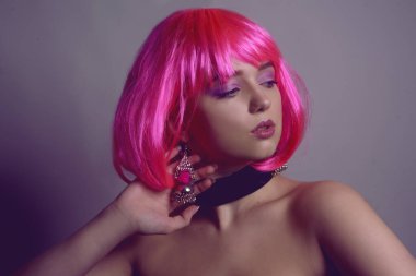 Pembe saçlı, şık bir kızın portresi. Modaya uygun küpeler, gümüşlü pembe küpeler. Mücevherler, aksesuarlar. Damalı ve varlıklı şık bir kız. Pembe makyajlı kız. Profesyonel makyaj..