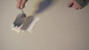 Adam tamir ile meşgul. Erkek eller düz bir yüzeyde spatula ve macun tutarlar. Onarım.