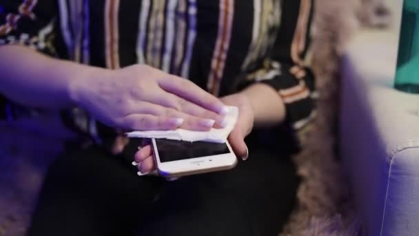 여자는 전화기를 살균제로 조심스럽게 코로나 바이러스 박테리아 로부터 자신을 보호하기 — 비디오