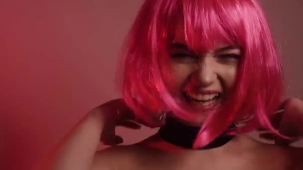 粉红短发的女孩 一个有着长长的粉色耳环和化妆品的模特 视频中的女孩笑了 摆姿势 摸她的头发 发疯了 时尚视频肖像 — 图库视频影像