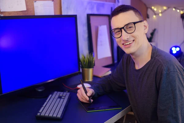 一个人拿着石碑和钢笔在家里干活 格里芬的设计师 一个男人看着一个绿色的屏幕电脑 一个人从事自由职业 正在学习新技术 远程学习 — 图库照片