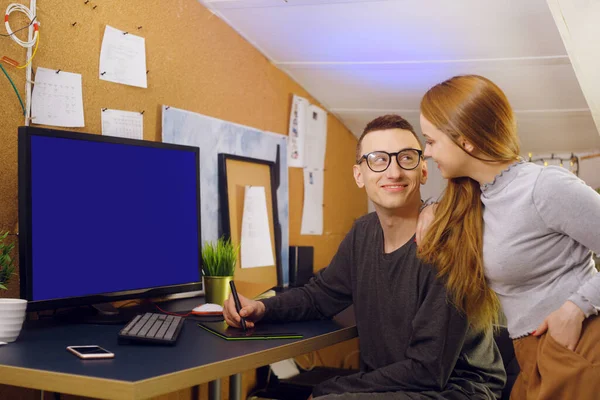 A couple with a dog are running. A man works on a graphic tablet with a dog in his arms, shows his girlfriend a computer, a green screen. A girl looks at how her boyfriend works at home. General business
