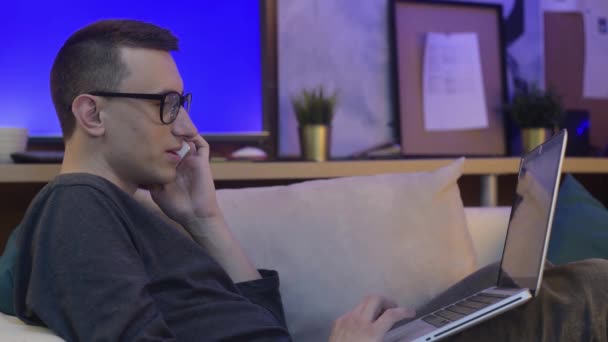 Evdeki Adam Elinde Dizüstü Bilgisayarla Kanepede Oturuyor Telefonla Konuşuyor Adam — Stok video