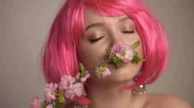 Cilt bakımı, bahar, portre, pembe çiçekli güzel bir model, filizler, tomurcuklar. Bahar başlangıcını miras alır. Çiçeklerden esinlenerek yapılan zarif pembe makyaj. Pembe saç.