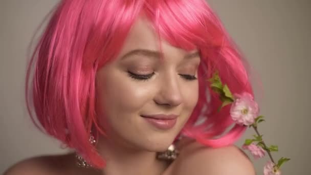 肖像画 ピンクの花 芽を持つ美しいモデルの女の子 春の始まりを受け継ぐ 花にインスパイアされた繊細なピンクのメイク ピンクの髪 — ストック動画
