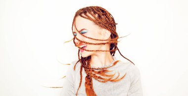 Rasta saçlı, örgülü saçlı, dans eden, 80 'lerin tarzında bir model. 90 'lı yaşlarda, parlak mavi makyajlı. Beyaz arka planda DJ kız pozu. Modelin eski tarzdaki sürüş fotoğrafı.