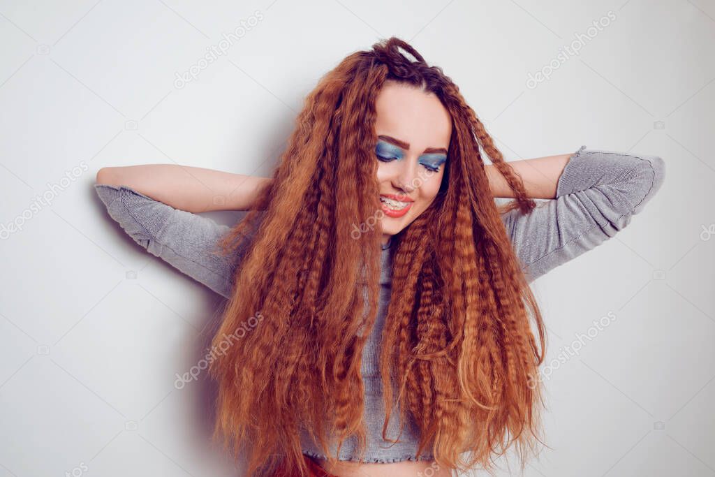 Girl with curled voluminous hair, model with hairstyle in the style of the 80s. 90s, with bright blue make-up. Hair care, brunette red-haired girl with long hair, curling curls, corrugation hair