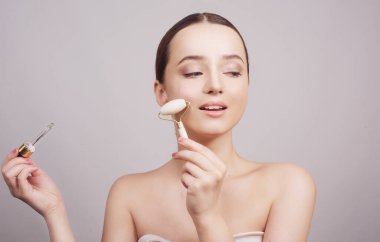 Güzel esmer bayanın yüzüne pipetle kozmetik yağ sürdüğü yakın plan. Güzellik terapisi kavramı.