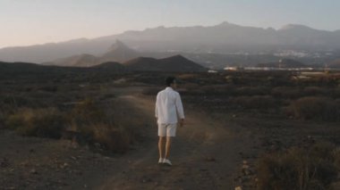 Beyaz elbiseli bir adam gün batımında bir yaz adası boyunca yürüyor. Bir gezgin dağlarda, taşlarda, inanılmaz doğanın ortasında yürür. Atmosfer video yazıName