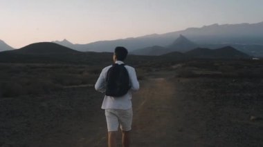 Sırt çantalı bir gezgin adadaki dağlara gider. Beyazlı bir adam özgürlüğün kokusunu içine çeker, doğayla bütünleşir. Arka planda gece şehri.