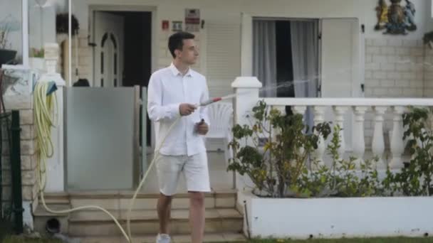 Bir Adam Villasının Yakınındaki Bir Hortumdan Çimenleri Suluyor Bahçede Beyaz — Stok video