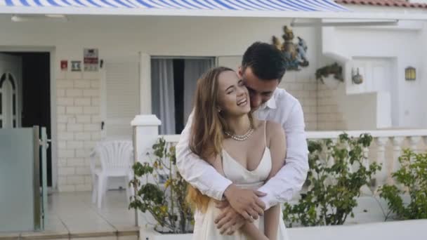 别墅后面的一对夫妇正在院子里放松 他们正在享受蜜月 欢笑和跳舞 婚礼之旅 白衣情侣彼此相爱 — 图库视频影像