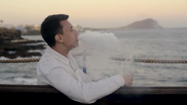 一个人坐在长椅上抽着烟 那家伙在看大海 一个人凝视着远方 欣赏风景 — 图库视频影像