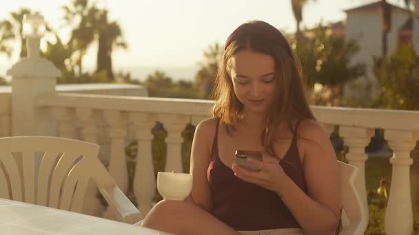 Een Meisje Zit Het Terras Tegen Achtergrond Van Zonsondergang Zomerdageraad — Stockvideo