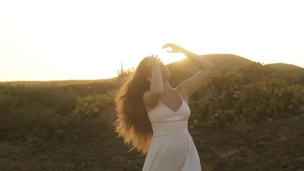 女孩在山中跳舞 太阳在她的头发 背光从日落 金发金发女人 长发舞曲 音乐录影带 夏之岛 穿着白衣的快乐女孩 — 图库视频影像