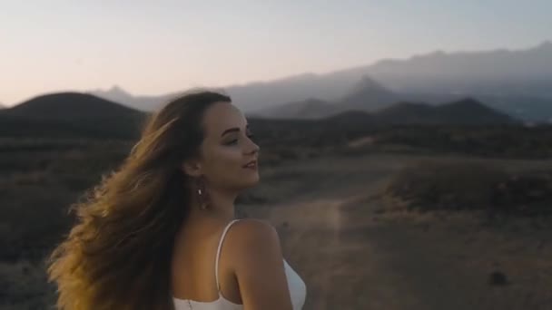 豪華な長髪の少女が山や豪華な自然を背景に踊り ポーズをとっています 島の夕日 大気中の音 公開ビデオ 自然との団結 — ストック動画