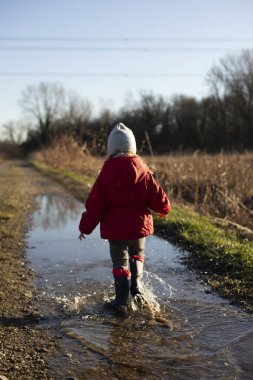 Su birikintisinde köpüklerle yürüyen çocuk..