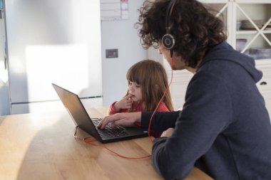 Young father working from home with little daughter during covid-19 lockdown. Child looking at dad's laptop while smartworking during social isolation. clipart