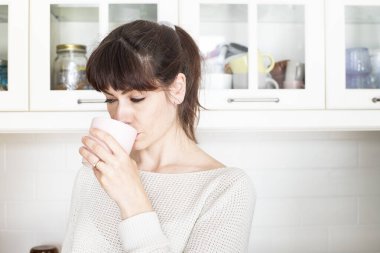 Kâküllü ve at kuyruklu beyaz bir kadın sabahları beyaz, parlak bir mutfakta bir fincan kahve içiyor. Uzaklara bakıyorum..