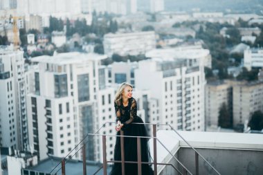 Çatıda poz siyah elbiseli kırmızı dudaklar ile çekici sarışın