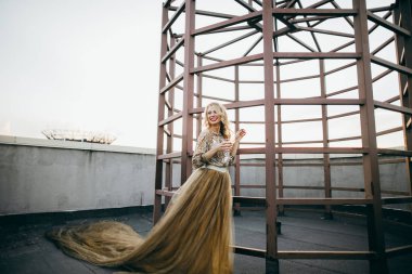 Cam çatı üzerinde tutarak altın elbise kırmızı dudaklar ile zarif gelin