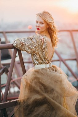Çatıda poz altın elbise zarif gelin