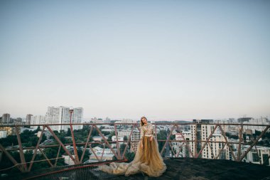 Altın elbise ve çatıda poz zarif kadın