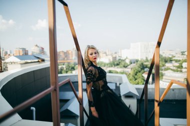 Çatıda poz siyah elbiseli kırmızı dudaklar ile çekici sarışın