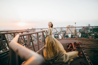 Çatıda gülümseyen altın elbise kırmızı dudaklar ile zarif kadın