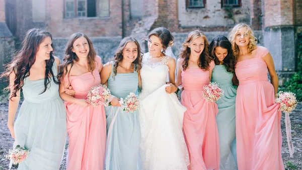 tender bride with smiling bridesmaids dressed in long elegant dresses