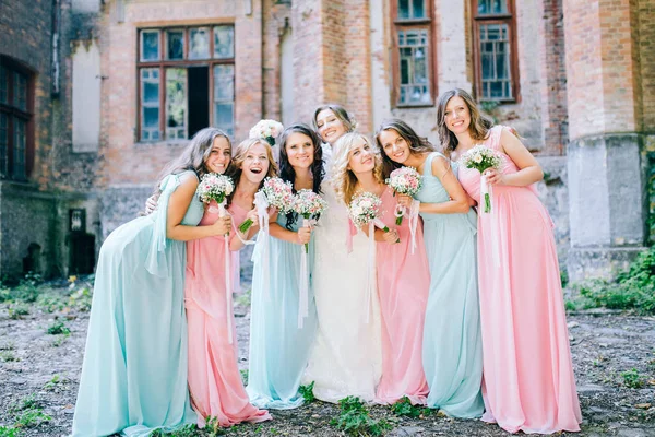 tender bride with smiling bridesmaids dressed in long elegant dresses