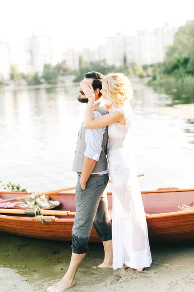 young wedding couple near  boat. Woman closing eyes of man