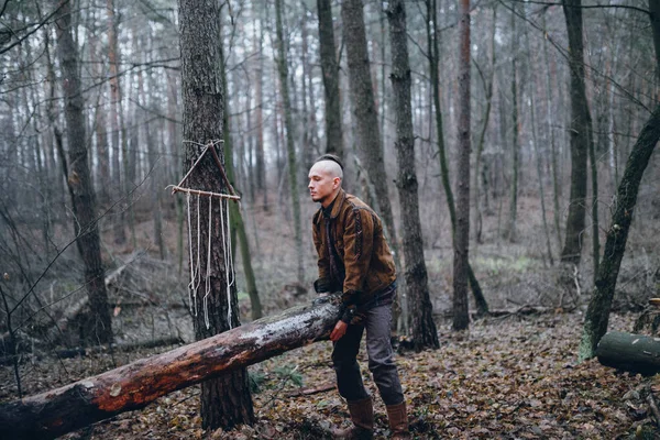 秋の森でログを持ち上げる若い男 — ストック写真