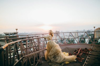 Çatıda poz altın elbise zarif gelin