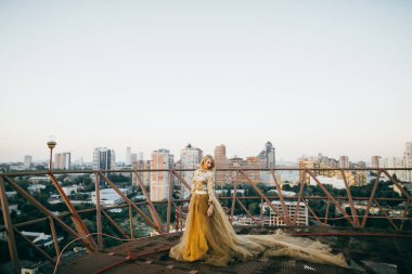 Çatıda poz altın elbise zarif gelin