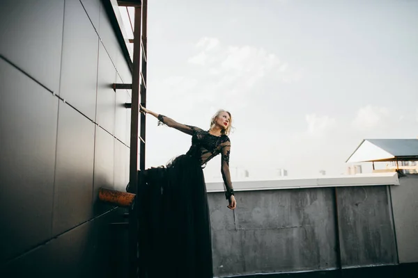 Attractive blonde in black dress posing on  ladder